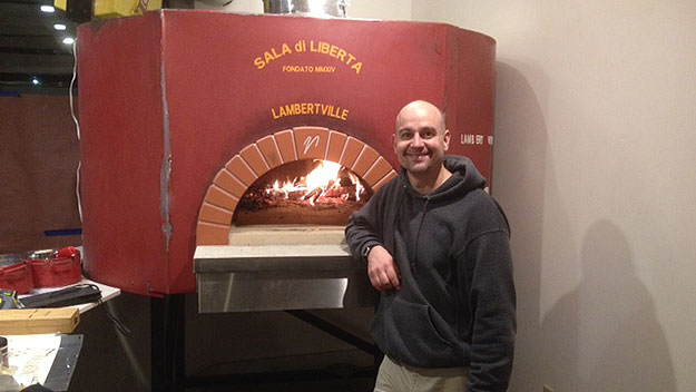 (Chris Bryan of Liberty Hall Pizza, at their wood-fired brick oven.  Photo provided)