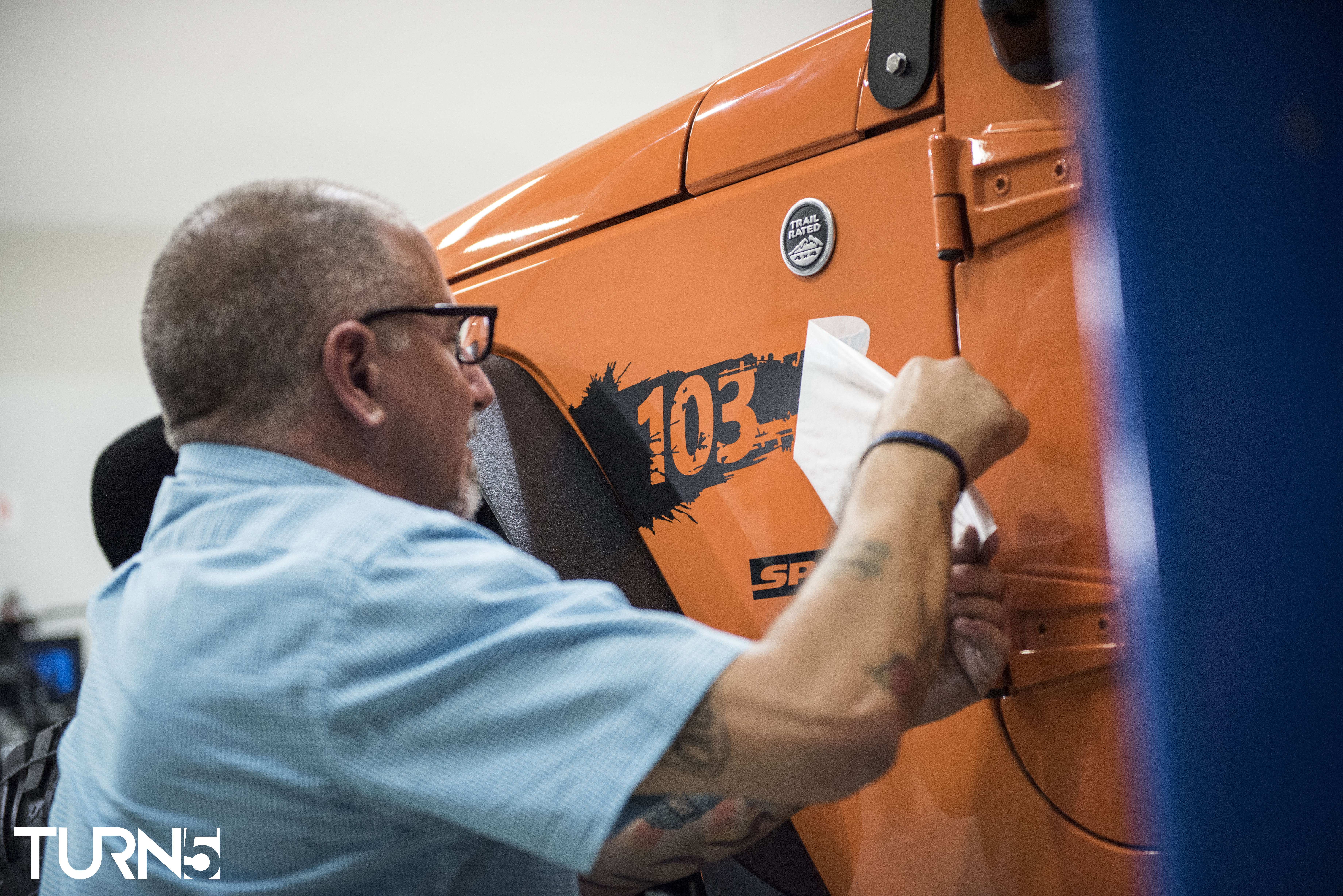 George Dorman, father of Officer Chris Dorman, placing the custom vinyl decal of his son's badge number on the 2012 Jeep Wrangler. (credit: Turn5)